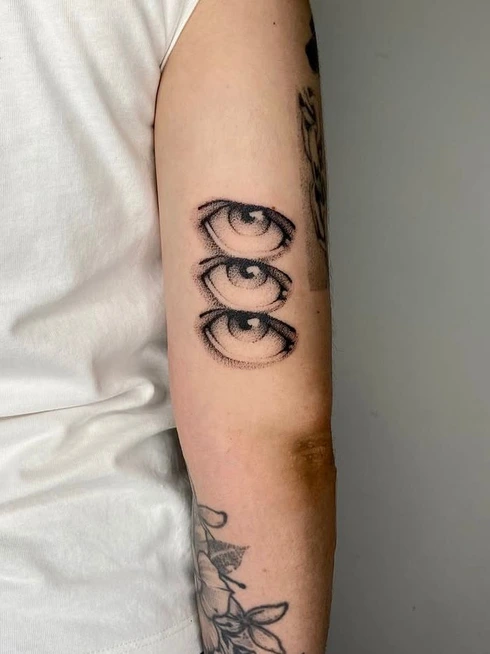 Tres ojos en puntillismo sobre el brazo